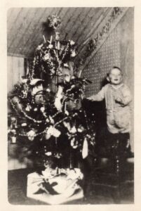 Omer Espe standing on chair by Christmas tree in 1919